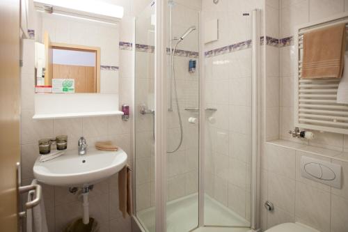 翁根雪绒花酒店的带淋浴、盥洗盆和卫生间的浴室