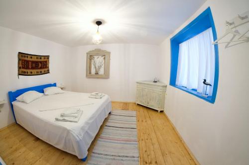茹里洛夫卡La Lipoveni的卧室配有白色的床和蓝色的窗户。