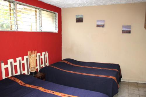 圣萨尔瓦多西梅纳斯宾馆的一间卧室设有两张床和红色的墙壁