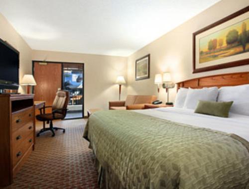 Urbandale得梅因华美达热带度假村/会议中心度假酒店的酒店客房设有一张大床和一张书桌。