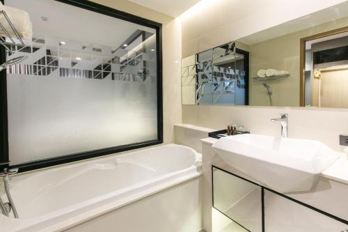武里南The Crystal Hotel Buriram - formerly X2 Vibe Buriram的浴室配有白色浴缸和水槽