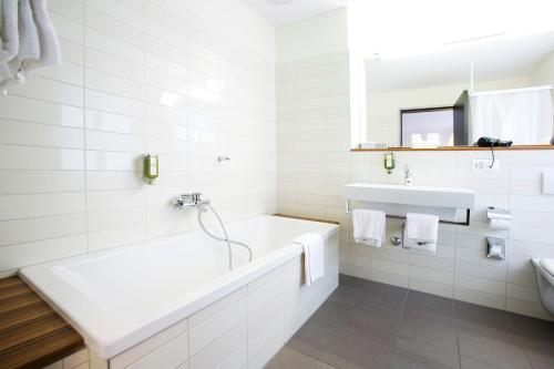 奥尔滕阿斯托利亚酒店的白色的浴室设有浴缸和水槽。