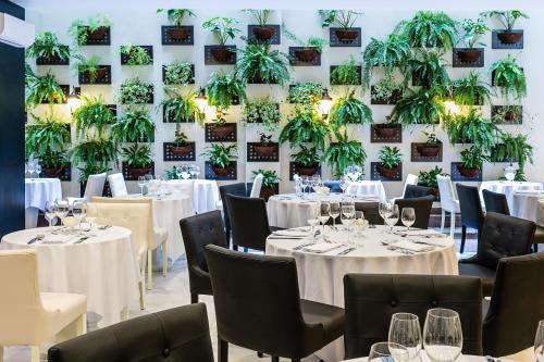 里约热内卢Nobile Hotel Copacabana Design的餐厅墙上挂有白色桌椅和植物