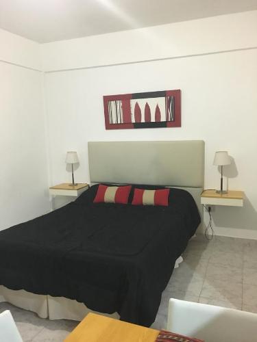科隆Apartamento Los Abuelos的一间卧室配有一张黑色床、两张桌子和两盏灯。