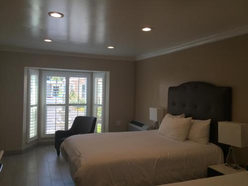 洛杉矶皇家酒店 - 近好莱坞环球影城的卧室配有床、椅子和窗户。