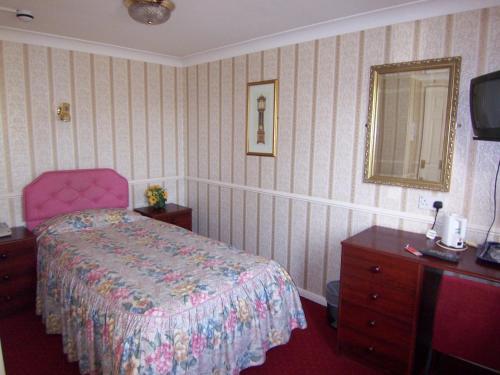 雷丁老羊酒店的一间卧室配有一张床、梳妆台和镜子