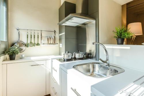 赫罗纳弗拉特里巴拉斯特里斯公寓的白色的厨房设有水槽和炉灶。