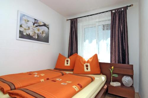 萨尔茨堡海林阁公寓的一间卧室配有两张带橙色枕头的床和窗户。