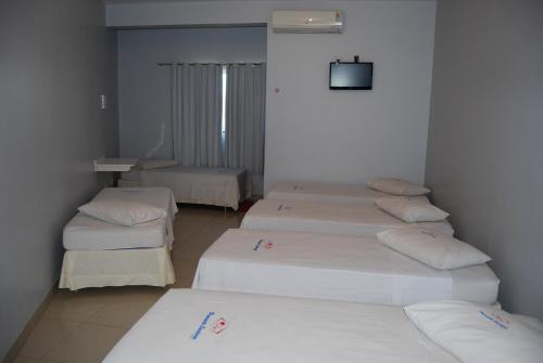 特林达迪Pousada Santana - Trindade Goiás的一间设有三张床和一台电视的房间