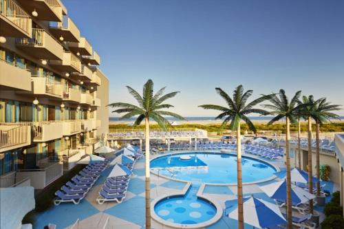 威尔伍德克拉斯特Pan American Oceanfront Hotel的一个带游泳池、椅子和棕榈树的度假村
