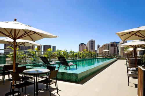 巴西利亚Intercity Brasilia Led Aguas Claras的一个带桌椅和遮阳伞的游泳池