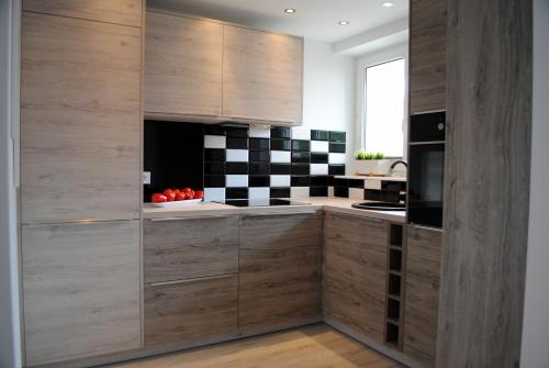 科沙林Apartament 1Maja的厨房配有木制橱柜和黑白格子墙