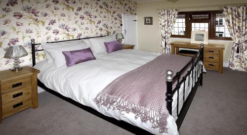 林肯Rose Cottage的一间卧室配有一张带紫色枕头的大床