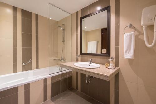 波罗维茨波罗维兹雄狮酒店的一间带水槽、浴缸和镜子的浴室