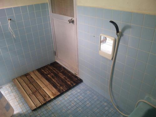 本部冲绳本部町旅馆的浴室铺有木地板,设有淋浴间。