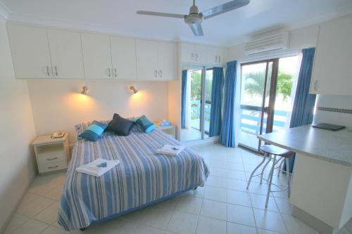 Shute Harbour珊瑚酒店的一间卧室配有一张床,厨房配有桌子