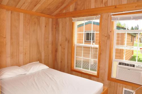 Elkhart LakePlymouth Rock Camping Resort Deluxe Cabin 16的一间卧室设有一张床和两个窗户。