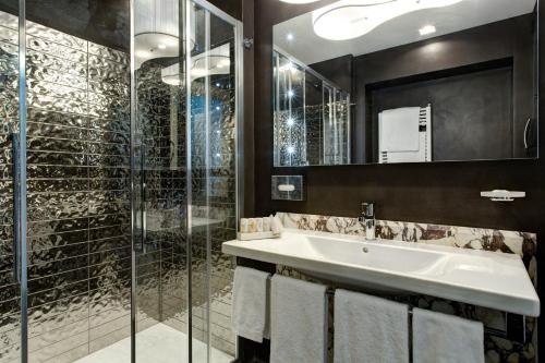 罗马Mascagni Luxury Rooms & Suites的一间带水槽和玻璃淋浴的浴室