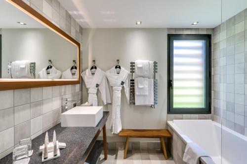 圣特罗佩Kube Saint-Tropez的一间带水槽、浴缸和镜子的浴室