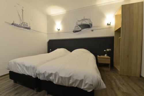 Dinteloord天堂西酒店的一间卧室配有一张铺有白色床单的床,墙上有小船。
