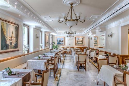 罗马Tmark Hotel Vaticano的一间带桌椅和吊灯的餐厅