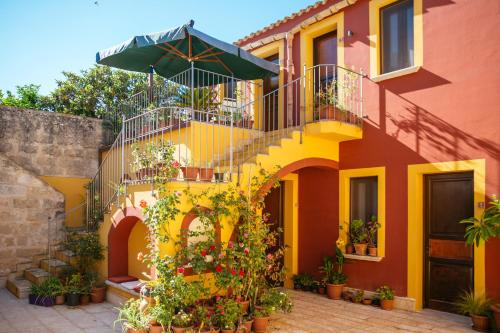 库斯托纳奇巴格里奥卡塔拉诺酒店的黄色和橙色的房子,设有楼梯和雨伞