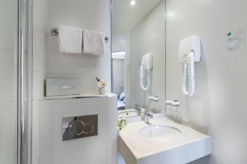 凡尔赛Logis Hôtel - La Résidence du Berry的白色的浴室设有水槽和镜子