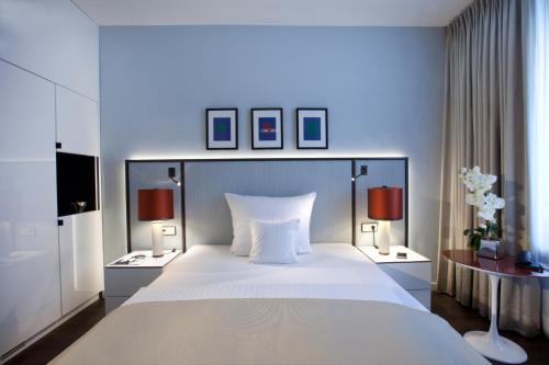 波恩AMERON Bonn Hotel Königshof的一间卧室配有一张带两盏灯的大型白色床。