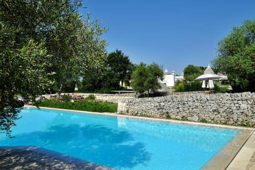 马丁纳弗兰卡Masseria Trulli e Vigne的一座大型蓝色游泳池,毗邻石墙