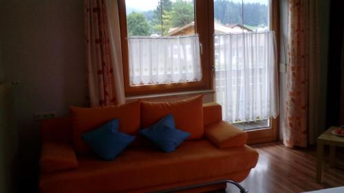 罗伊特Haus Hämmerle的带窗户的客房内配有带蓝色枕头的橙色沙发