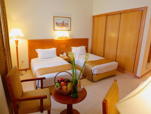 沙迦沙迦普瑞米尔度假酒店的酒店客房,配有一张床和一张桌子,还有一碗水果