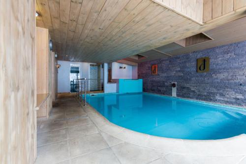 拉克吕萨阿尔卑酒店的一座大型游泳池,位于一座拥有木制天花板的建筑中