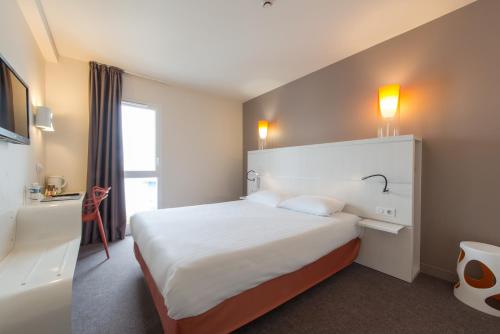 拉罗谢尔罗歇尔中心齐亚迪酒店 - 莱斯米尼蒙的一间设有大床和窗户的酒店客房