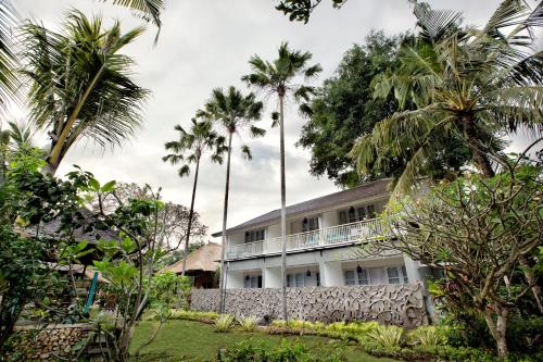 沙努尔萨伽拉田园酒店的一座棕榈树掩映的白色建筑