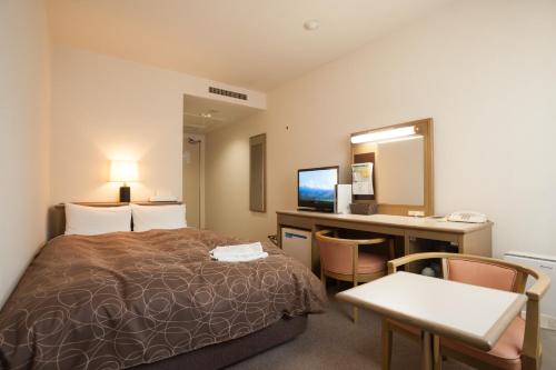 三原市亚萨酒店的配有一张床和一张书桌的酒店客房