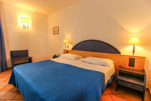 兰佩杜萨法国圣骑士酒店的一间卧室配有一张带蓝色毯子的大床