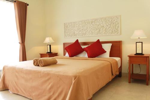 沙努尔莫娜民宿的一间卧室配有一张带红色枕头的大床