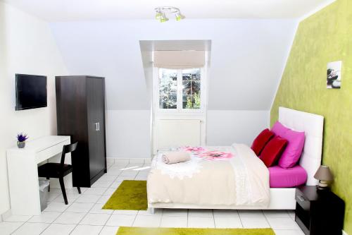 蒂艾L'Eden Orly Aéroport的一间卧室配有一张带粉色枕头的床和一张书桌