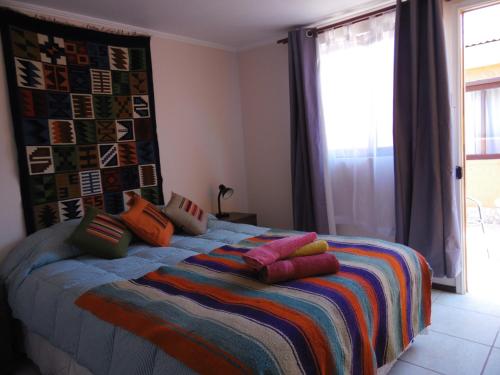 圣佩德罗·德·阿塔卡马坎普基地旅舍的一间卧室配有带色彩缤纷枕头的床。