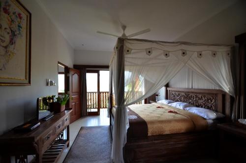 Tirtagangga三泰卡朗阿森别墅旅馆的一间卧室配有一张天蓬床和一台电视机