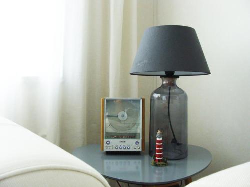 霍勒姆Chalet Zilt Ameland的玻璃桌上的一盏灯和一个钟,床上