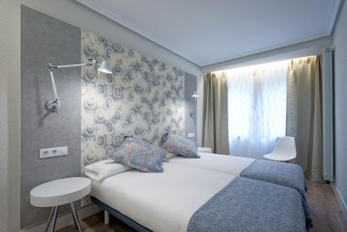 圣塞瓦斯蒂安Apartamento Zurriola Luxury - Surf Beach con aire acondicionado的酒店客房设有床和窗户。