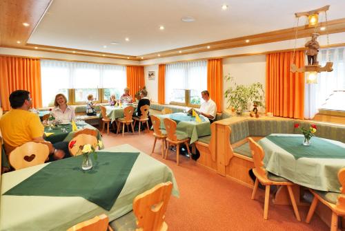 伦茨基希瓦尔德温克尔酒店的一间设有桌子的餐厅,有坐在桌子上的人