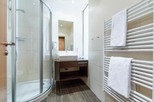 沃尔特湖畔韦尔登文森斯酒店的一间带玻璃淋浴和水槽的浴室
