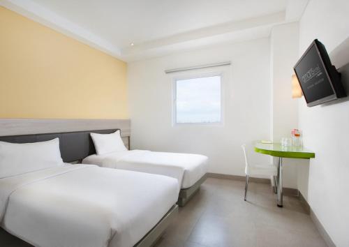 马卡萨佩塔拉尼爱玛瑞丝酒店 - 望加锡的酒店客房设有两张床和一张桌子。