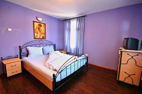 德里亚诺沃Private 4BR-2BA guest House Dryanovo with Pool and FREE Parking的一间卧室配有一张紫色墙壁的床和一台电视