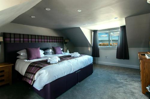 Bowmore路荷喜德酒店的一间卧室配有一张带紫色枕头的大床