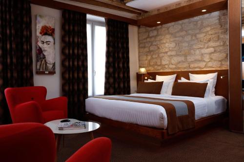 巴黎精选酒店的一间卧室配有一张大床和一张红色椅子