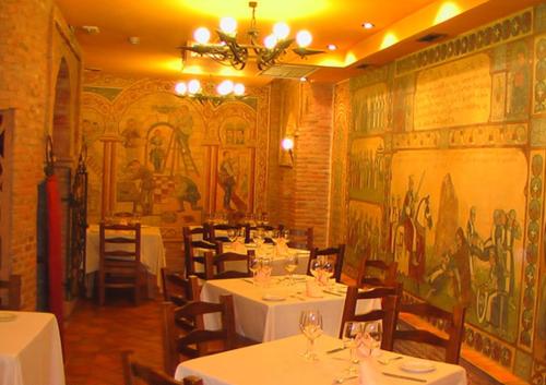 莱昂费尔南多旅馆的一间设有白色桌椅和壁画的餐厅