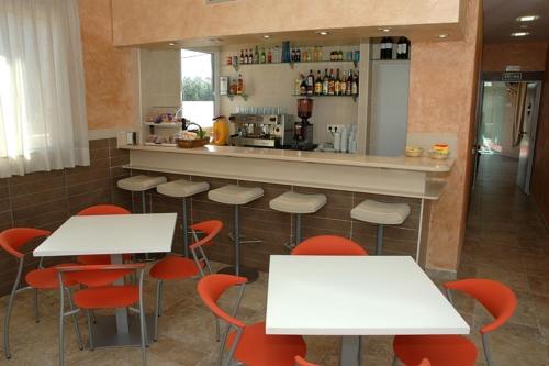 马德里劳斯考罗纳尔斯旅馆的餐厅内带白色桌子和红色椅子的酒吧